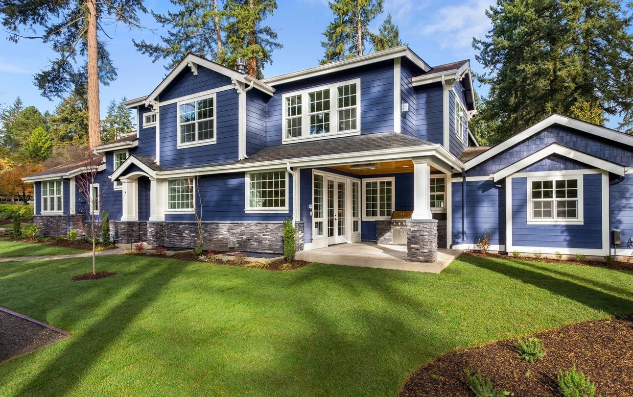 A blue house with white trim and green grass.