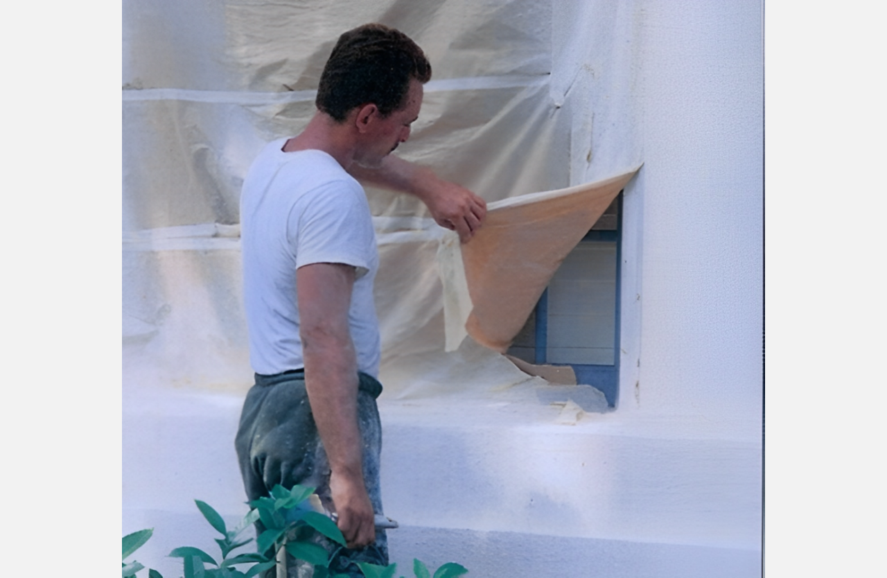 A man is putting up wallpaper on the wall.