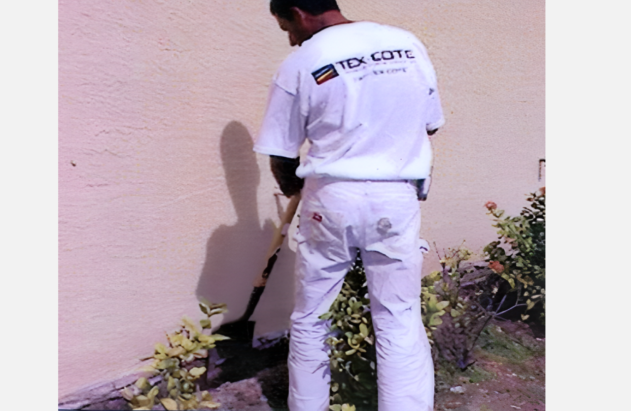 A man in white shirt and pants holding a broom.