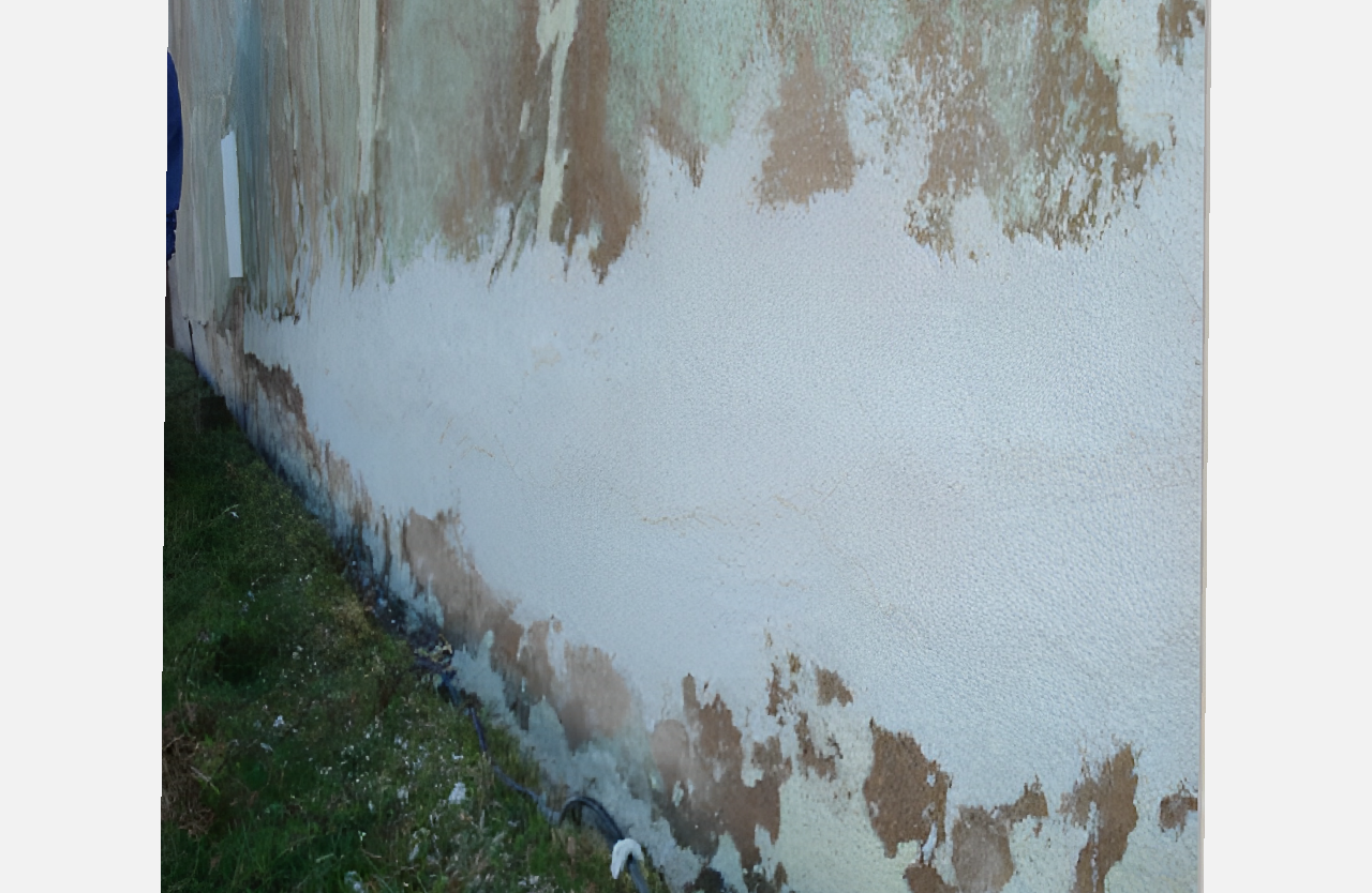 A wall with white paint and brown stains.