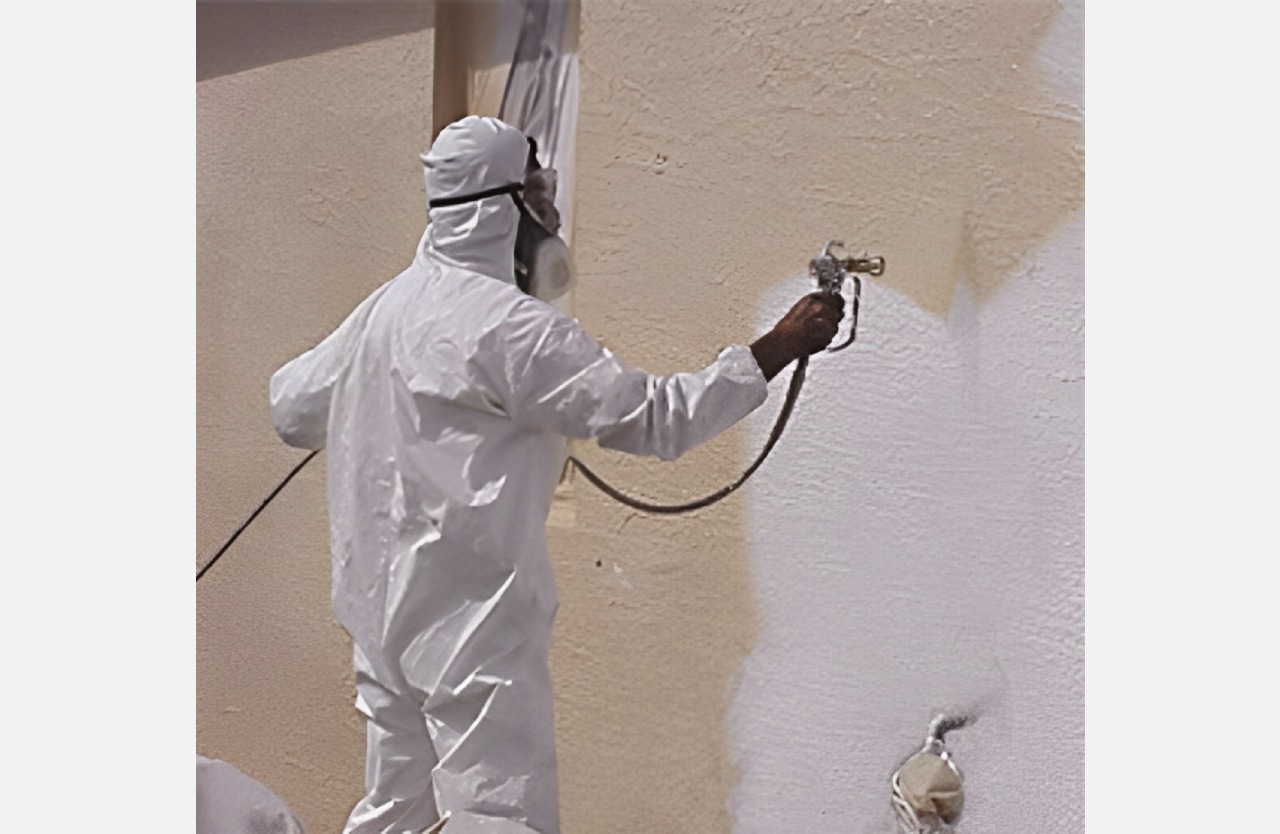 A person in white suit painting the side of a building.