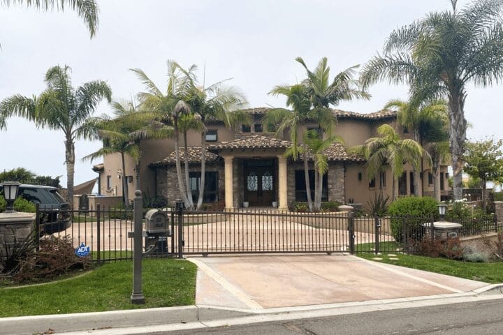 A large house with palm trees and a driveway.